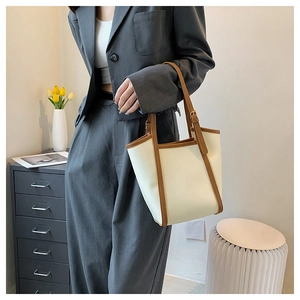 Detail of adjustable metal buckle and brown leather strap on contrast tote bag