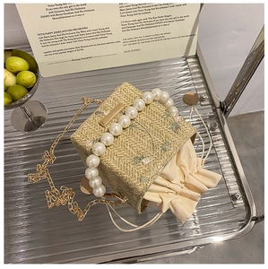 Détail du sac en paille avec broderie de feuilles, anse en perles et cordon de serrage
