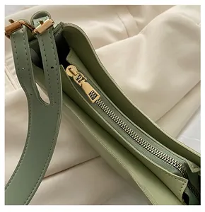 Detail of golden metal zipper and smooth leather on green minimalist shoulder bag