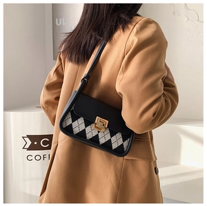 Detail of checkered saddle bag with gold metal clasp and leather strap for women