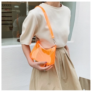 Close-up of bright orange transparent PVC shoulder bag with metallic buckle detail