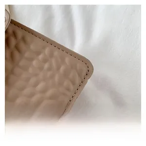 Détail du gaufrage à bulles et des coutures soignées sur ce petit sac à bandoulière