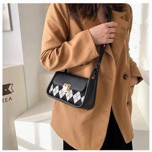 Detailed view of argyle pattern saddle bag with gold lock worn with a tan blazer