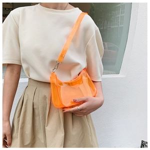 Close-up of orange transparent jelly bag with silver metal chain on woman shoulder