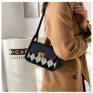 Detail view of retro plaid saddle bag with black leather flap and gold square buckle lock