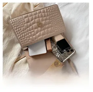 Aperçu de la capacité du sac beige gaufré crocodile avec des objets essentiels à l'intérieur