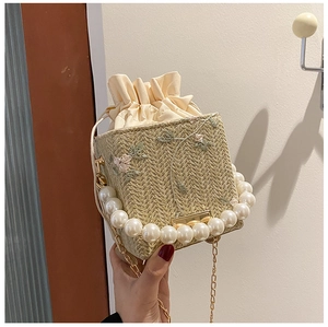 Gros plan du sac en paille tressée avec broderie florale et anse en perles élégante