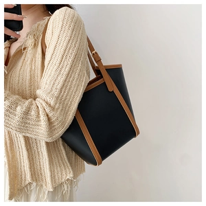 Close-up of a large contrast color leather tote bag shown on model's shoulder