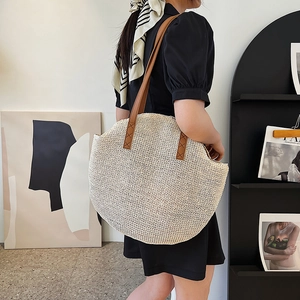 Minimalist beige woven semi-circle straw tote bag with brown leather shoulder straps