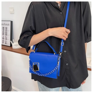 Detail of blue faux leather shoulder bag with bold gold chain link and metallic buckle