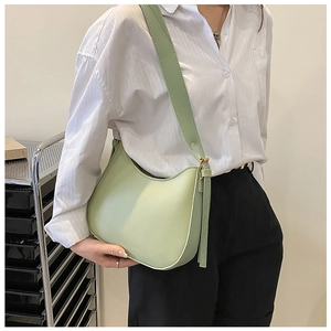 Detailed view of light green hobo bag with wide shoulder strap worn by a model