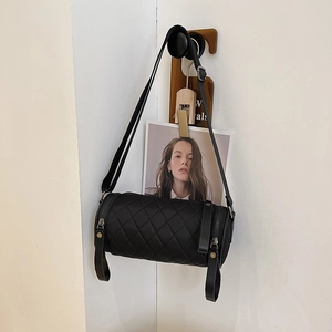 Quilted black cylinder crossbody bag with diamond stitching and adjustable strap