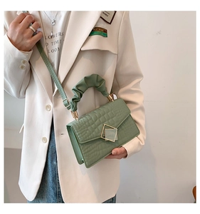 Détail du sac vert texture crocodile avec poignée froncée et boucle dorée chic