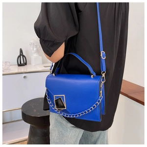 Close-up of royal blue crossbody bag with metal chain strap and geometric buckle