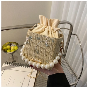 Détail du sac seau en paille avec broderie florale et grande poignée en perles