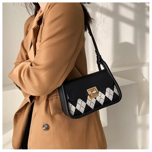 Detail view of the elegant leather strap and golden hardware on the checkered saddle bag