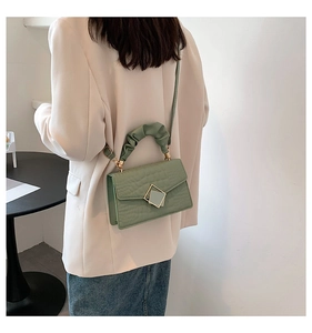 Gros plan sur la texture crocodile et la poignée plissée d'un élégant sac à main vert