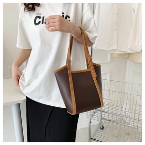 Macro detail of dark brown tote bag with contrast piping and textured synthetic leather