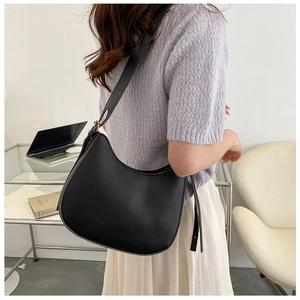 Back view of model wearing a minimalist black hobo bag on the shoulder indoors
