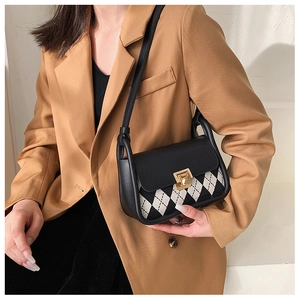 Detail of vintage plaid saddle bag with golden clasp worn over a tan blazer