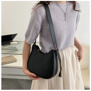 Detail of adjustable strap and metal buckle on matte black crescent shoulder bag