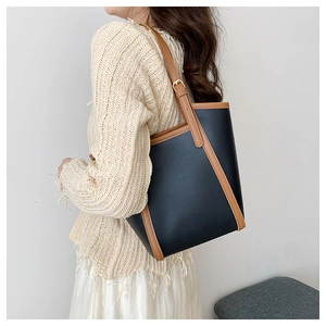 Detail of adjustable leather strap and color-block stitching on tote bag for work