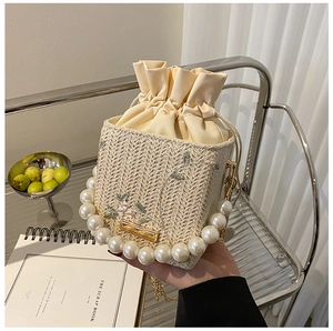 Détail du sac seau en paille avec anse en perles et broderie florale colorée