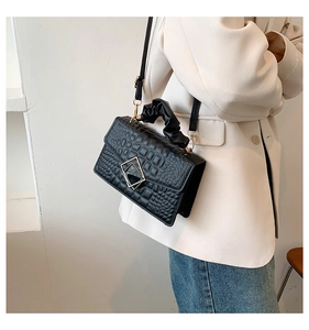 Détail du sac noir à texture crocodile avec boucle argentée et poignée froncée