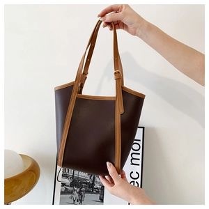 Detail of contrast-color leather tote bag with adjustable shoulder strap and metal buckle