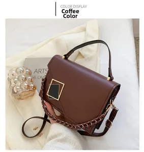 Detail of coffee brown matte leather handbag with metal buckle and woven chain strap