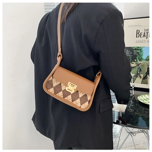 Detail of vintage argyle saddle bag with brown leather flap and gold lock closure