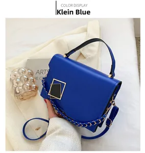 Detail of Klein Blue leather handbag showing gold geometric buckle and woven chain strap