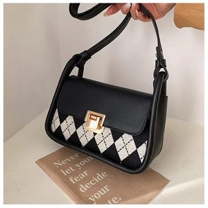 Detail of checkered saddle bag with black leather flap and golden twist lock closure