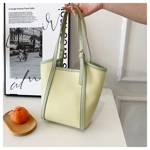 Detail of a contrast color tote bag with mint green handles and pale yellow PU leather
