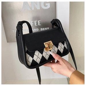 Detail of checkered saddle bag with black leather flap and gold metal snap buckle