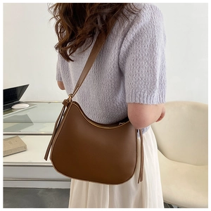 Detail view of the brown crescent hobo bag made of textured leather with adjustable strap