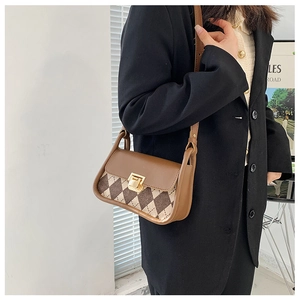 Close-up of vintage argyle saddle bag with gold clasp and brown leather strap details