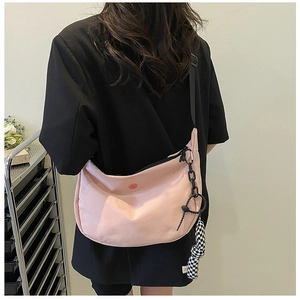 Détail du sac bandoulière rose en demi-lune avec breloque damier et sangle ajustable