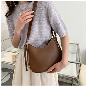 Close-up of brown half-moon shoulder bag with adjustable strap on a female model