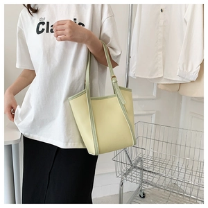 Detail of light yellow and mint green tote bag with adjustable shoulder straps and buckles