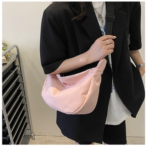 Détail du sac à bandoulière rose en forme de croissant avec une large sangle noire réglable