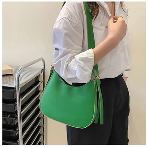 Vibrant green moon-shaped hobo bag worn on shoulder by model in a minimalist setting