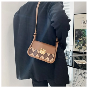 Close-up of retro plaid saddle bag with golden metal buckle and brown leather trim