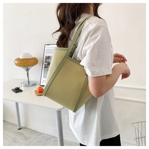 Detailed shoulder view of a large lime green tote bag with dark green edges on a model