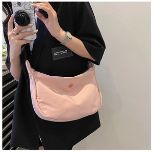 Détail du sac croissant en nylon rose clair montrant la texture mate et le logo rouge