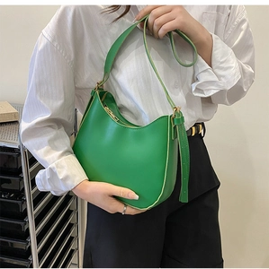 Chic bright green leather crescent bag with golden zipper on model shoulder
