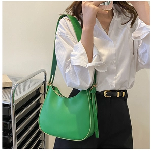 Close-up of green crescent underarm bag with gold metal buckle and adjustable strap