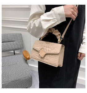Détail du sac beige en cuir crocodile avec poignée plissée et fermoir en métal géométrique