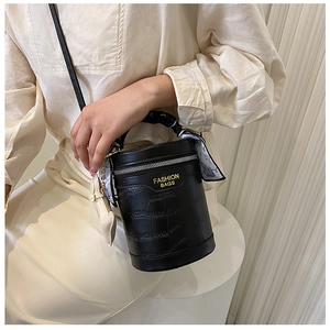 Close-up of black crocodile-embossed bucket bag with fashion print silk scarf handle