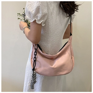 Sac hobo rose avec bandoulière réglable et nœud en damier porté par le mannequin